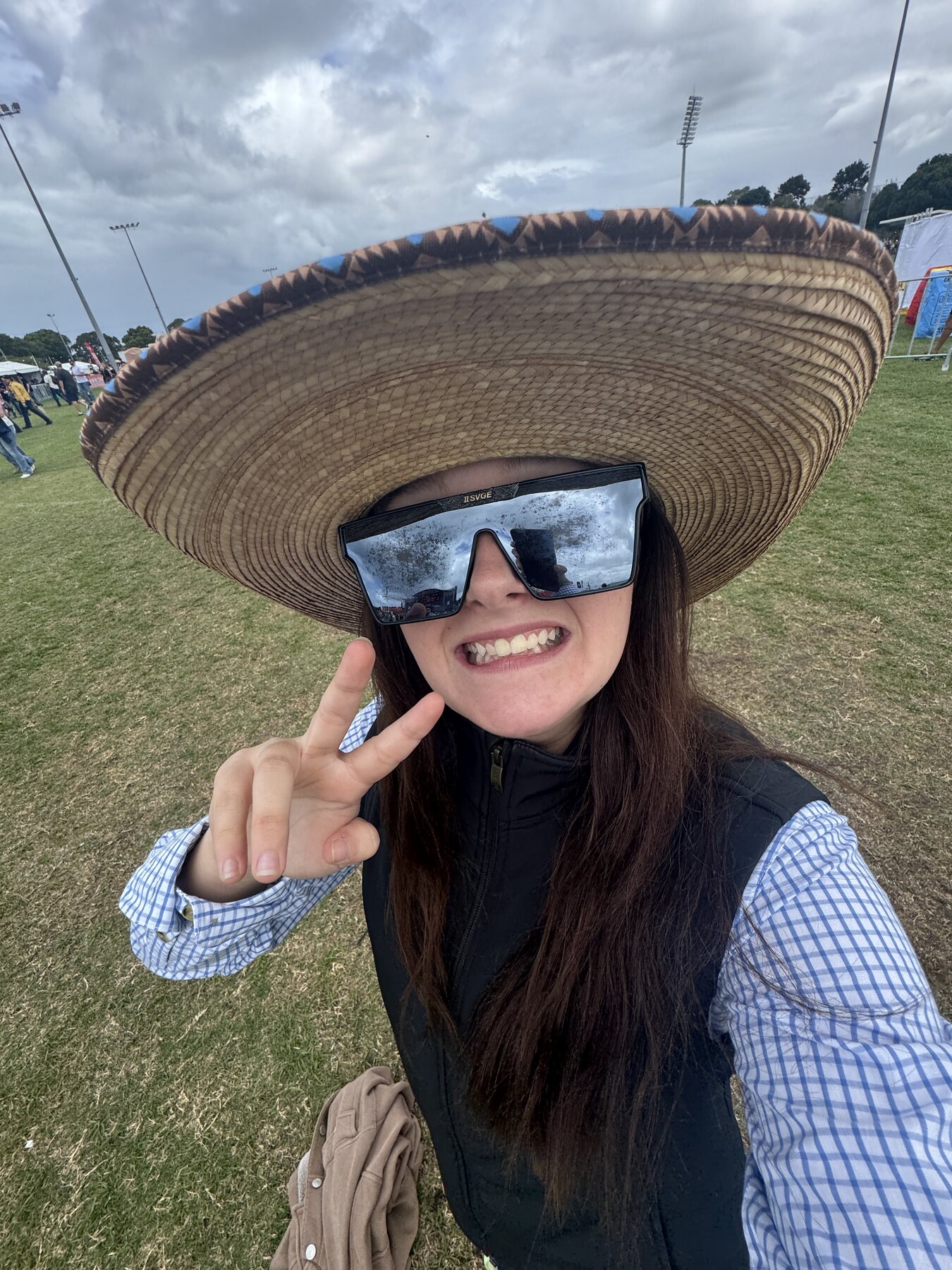 Festival attendee wearing an oversized straw hat and novelty sunglasses
