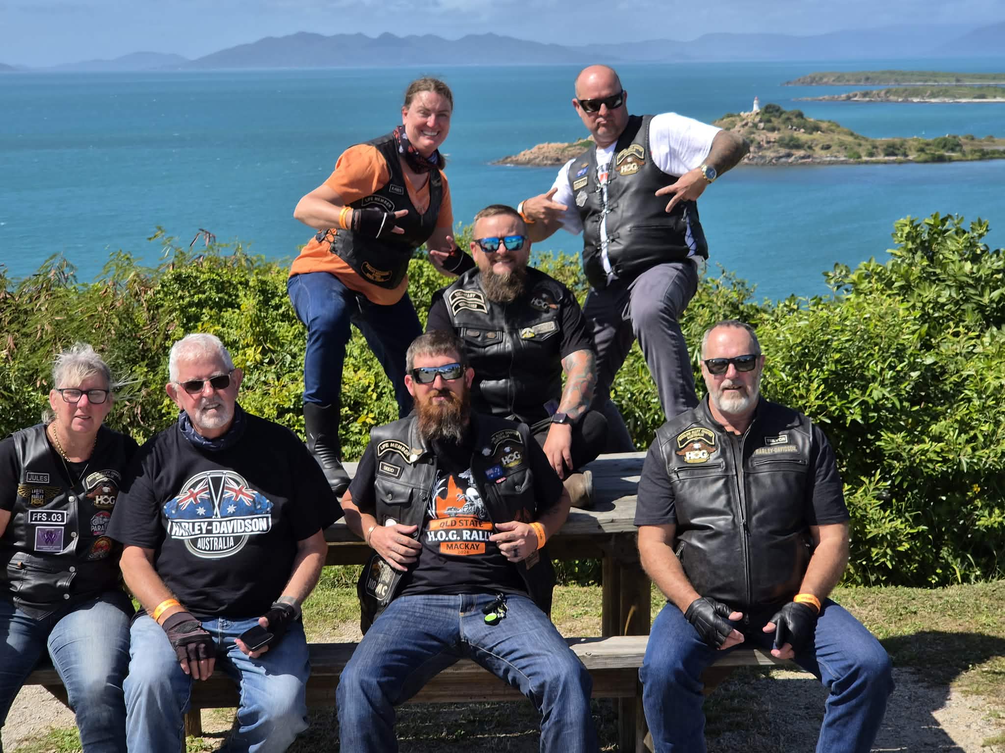 Seven rally riders posing together at the coastal lookout.