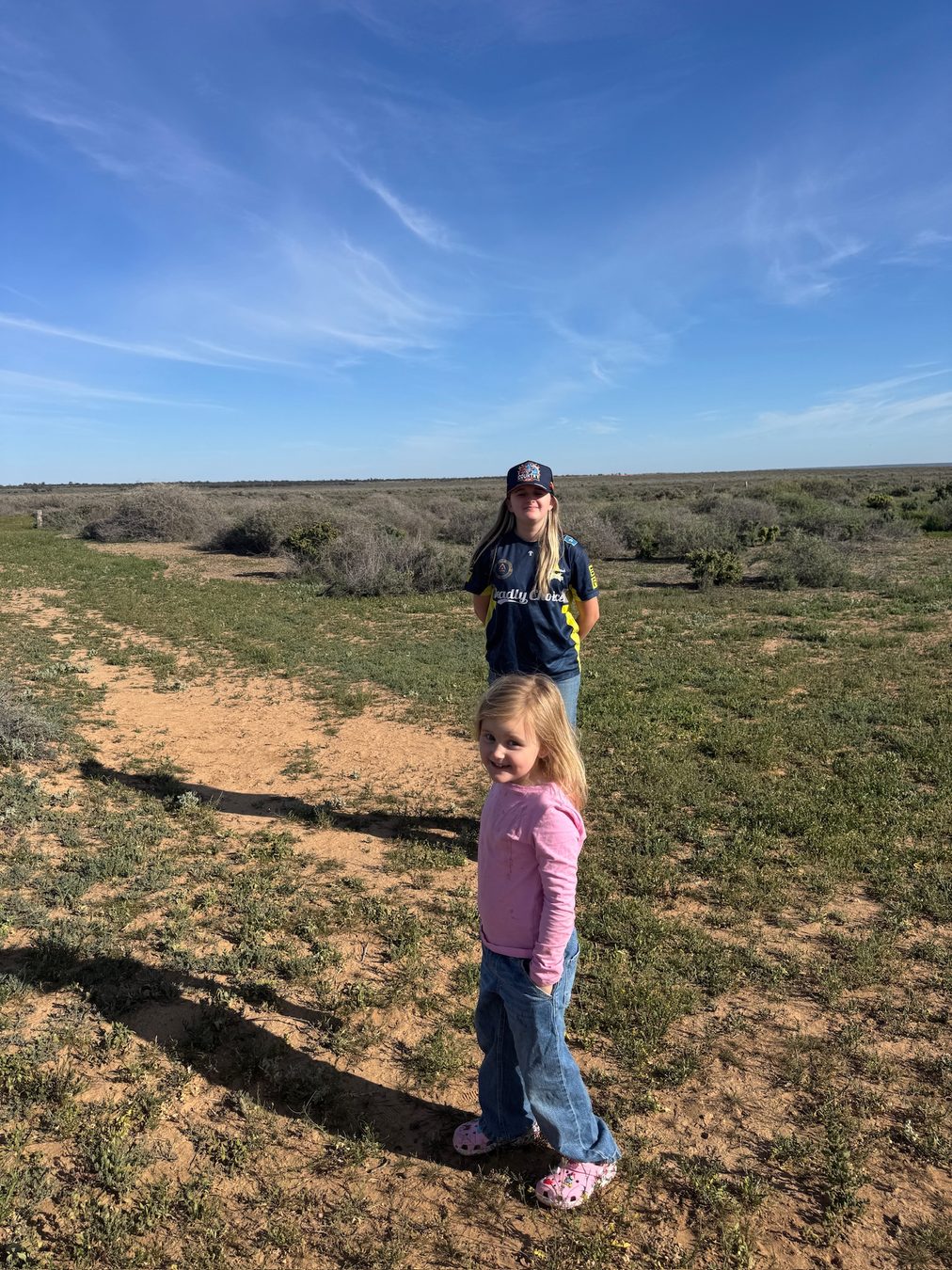 Family members walking along a sandy track through the scrub.